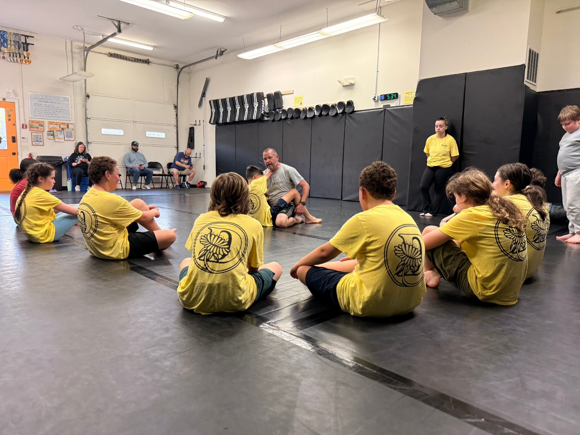 Coach instructing a circle of youth students during a Dandelion Jiu Jitsu class in West Haven